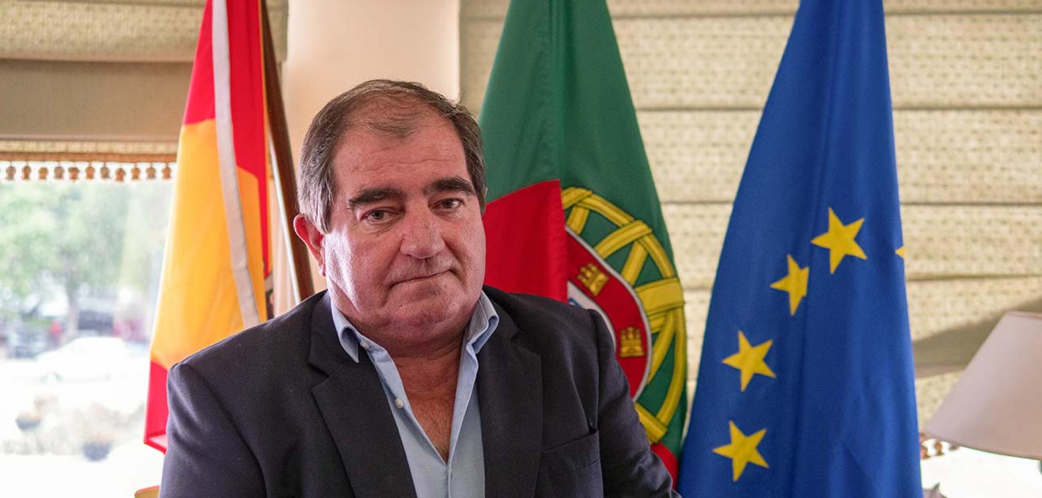 homem a pousar para foto com bandeiras atras