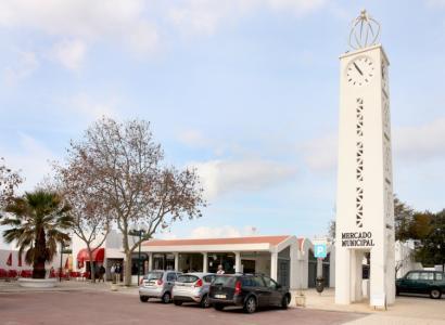 mercado 3 ccarros estacionados e uma torre relogio branca