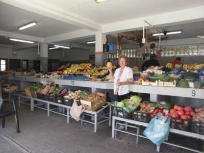 senhora segura um legume com bancadas de frutas a voltas