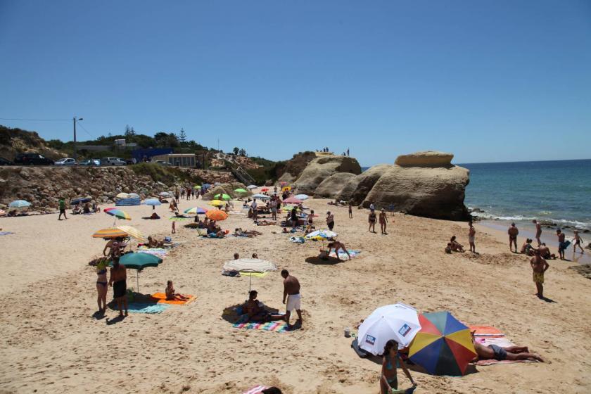 pessoas deitadas na areia com rochas atras