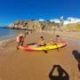 Duas crianças dentro de um kayak a entrar no mar na praia do peneco